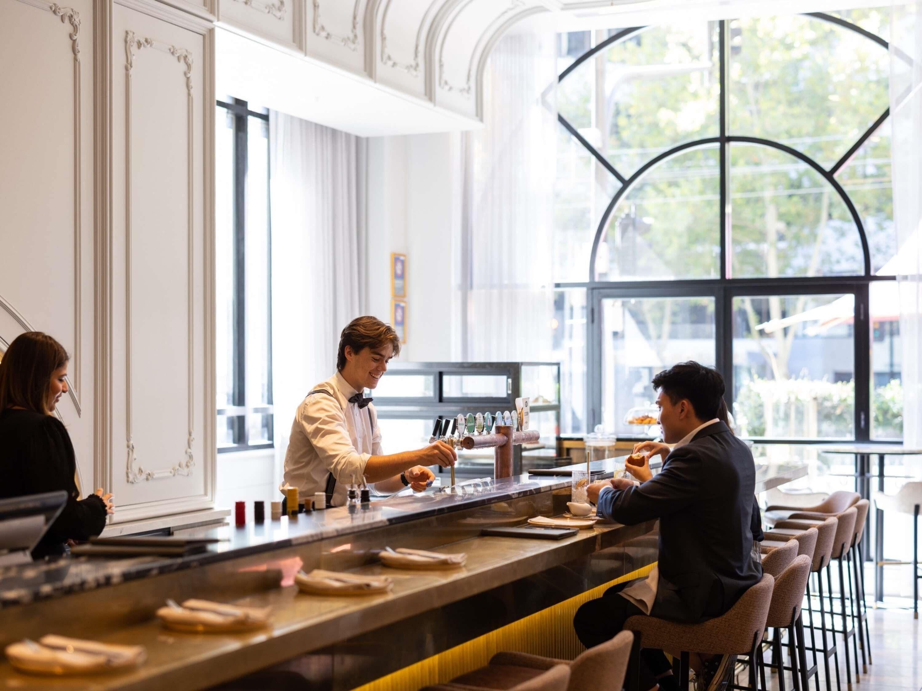 Eine Bar mit einer Theke, Barhocker und einem großen Fenster mit Blick ins Freie.