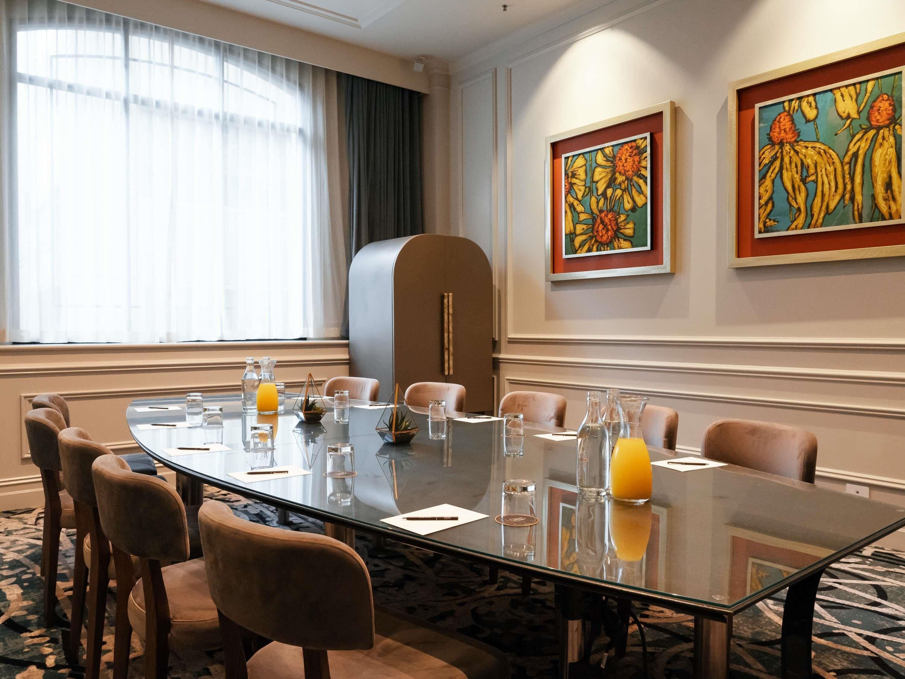 A conference room with a glass table, chairs, and artwork on the walls.