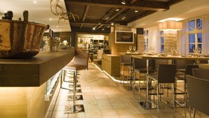 Ein Restaurant mit Barbereich, Holzbalkendecke und einer Wand aus Stein.