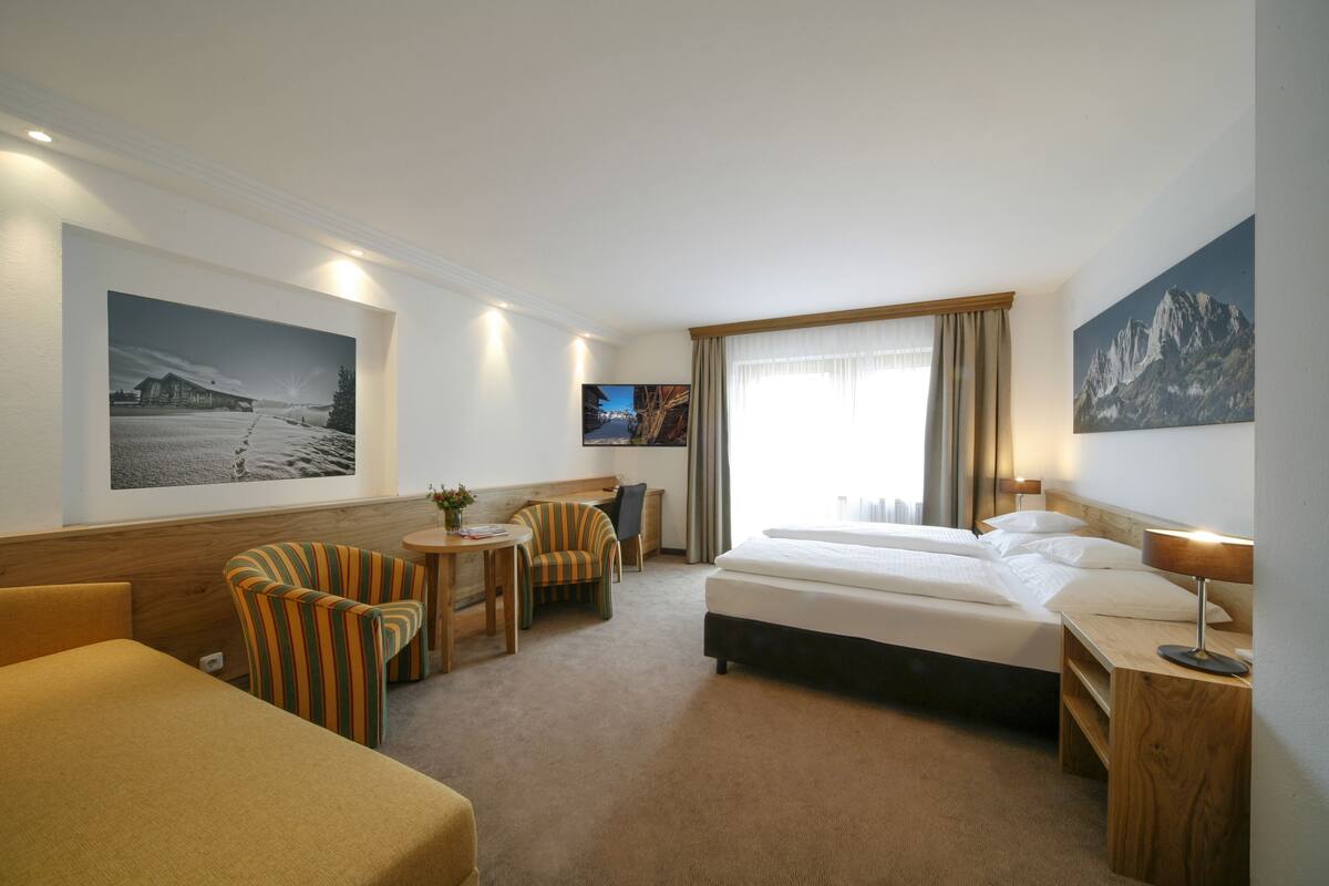 Une chambre d’hôtel avec un lit, un bureau, une chaise et un téléviseur.