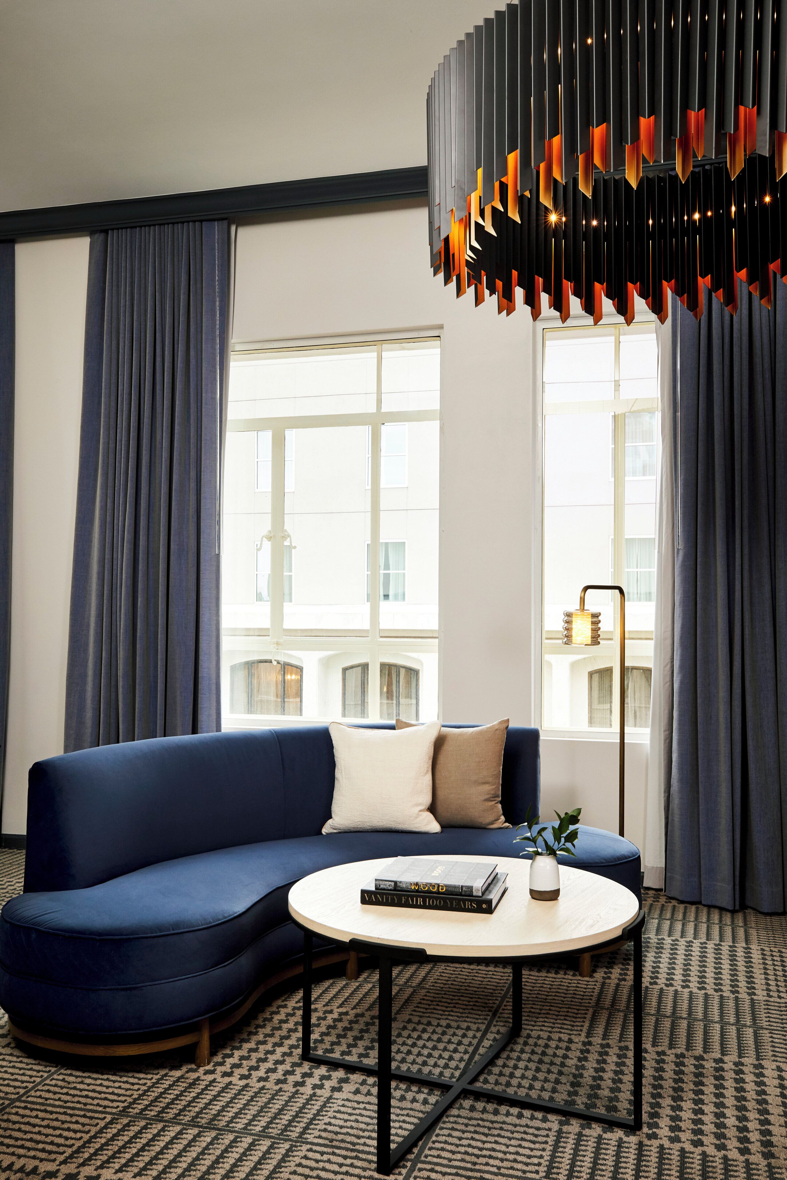 A modern living room with a blue sofa, a round coffee table, and a unique hanging light fixture.