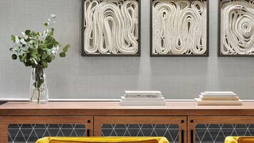 A modern living room with a yellow sofa, a round coffee table, and a decorative wall with abstract art.