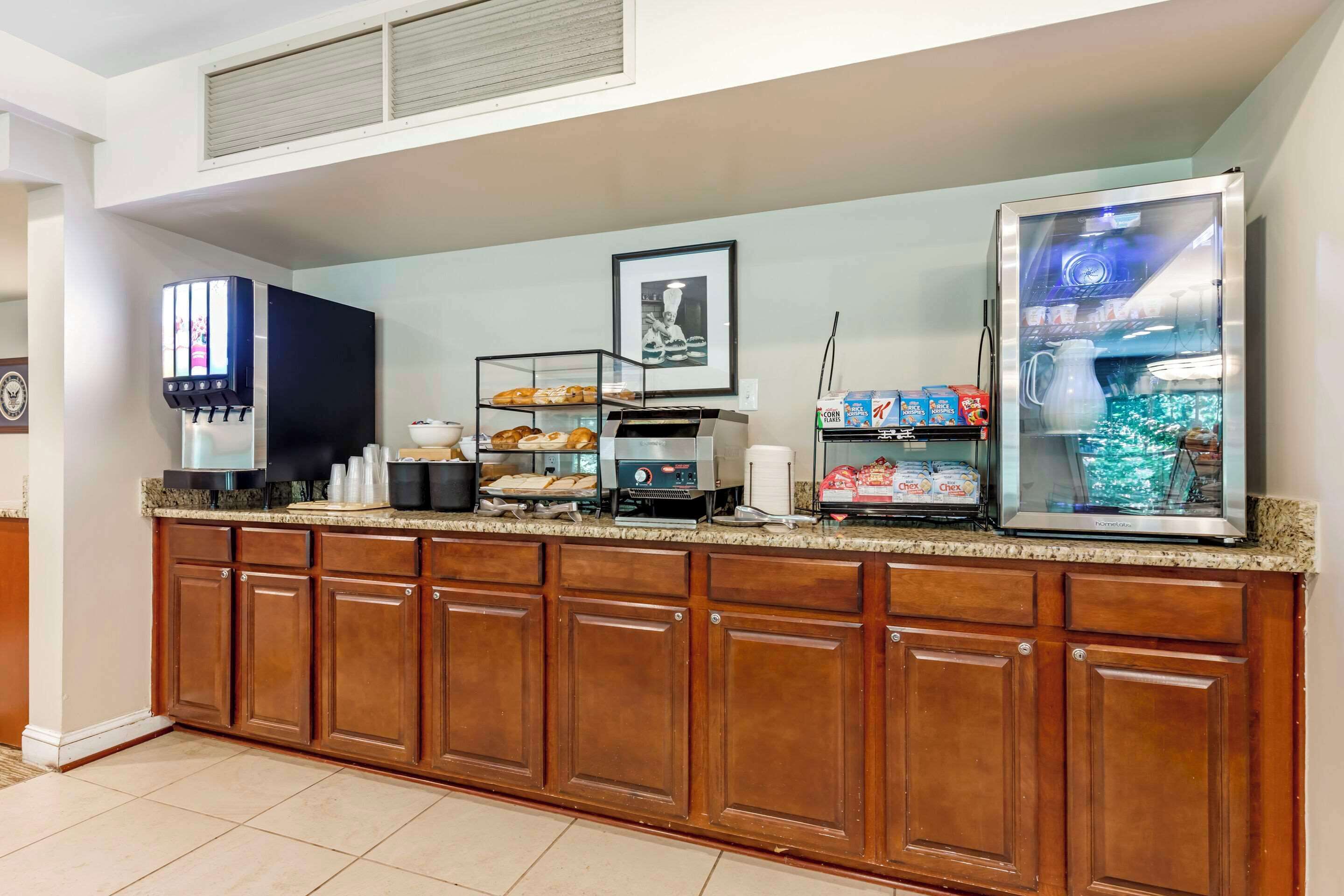 A hotel kitchen with a self-serve coffee station, a refrigerated display case, and a variety of baked goods.