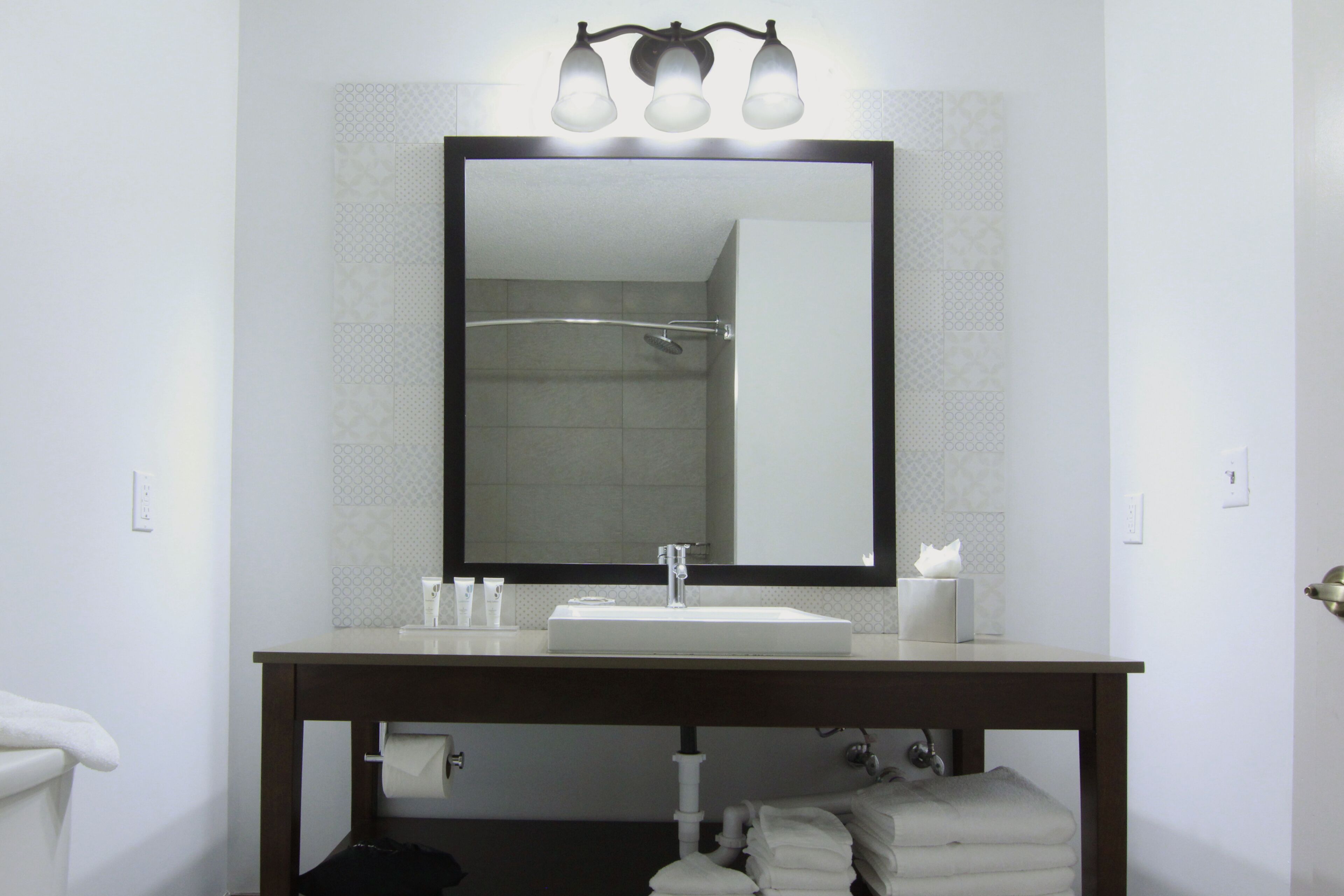 Une salle de bain avec un grand miroir, un lavabo et un porte-serviettes.