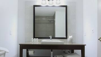 A bathroom with a large mirror, a sink, and a towel rack.