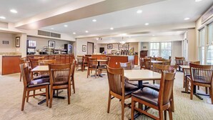 A spacious dining area with multiple tables and chairs, a central bar area, and large windows providing natural light. - Country Inn & Suites by Radisson, Annapolis, MD (Annapolis)