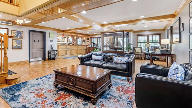 A spacious living room with a large wooden coffee table, a leather sofa, and a chandelier. - Country Inn & Suites by Radisson, Annapolis, MD (Annapolis)