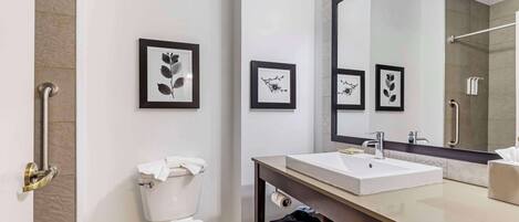 Un baño moderno con inodoro blanco, un espejo grande y obras de arte enmarcadas en la pared.