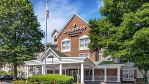 A Country Inn & Suites by Radisson building with a brick facade, white columns, and a green roof. - Country Inn & Suites by Radisson, Annapolis, MD (Annapolis)