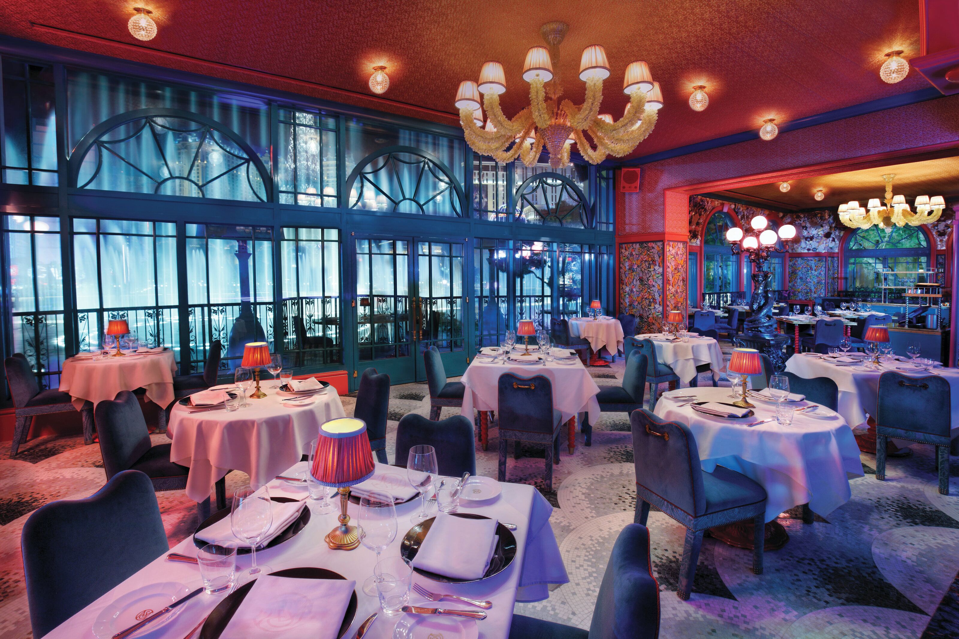 Een restaurant met ronde tafels, stoelen en kroonluchters.
