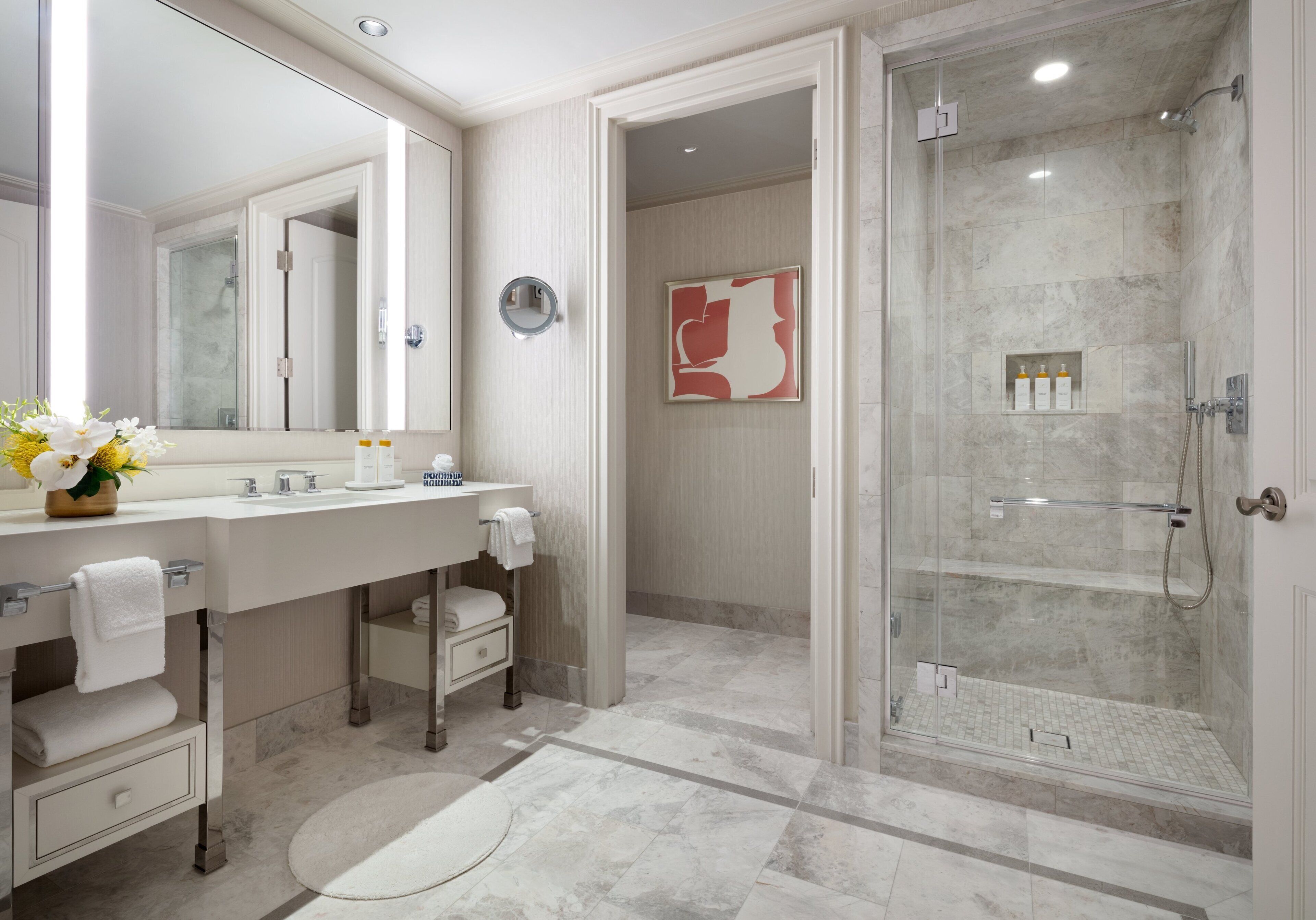 A modern bathroom with a large mirror, a vanity with a sink, a shower area, and a tiled floor.