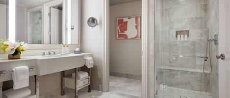 Un baño moderno con un espejo grande, tocador con lavamanos, zona de ducha y suelo de baldosas.