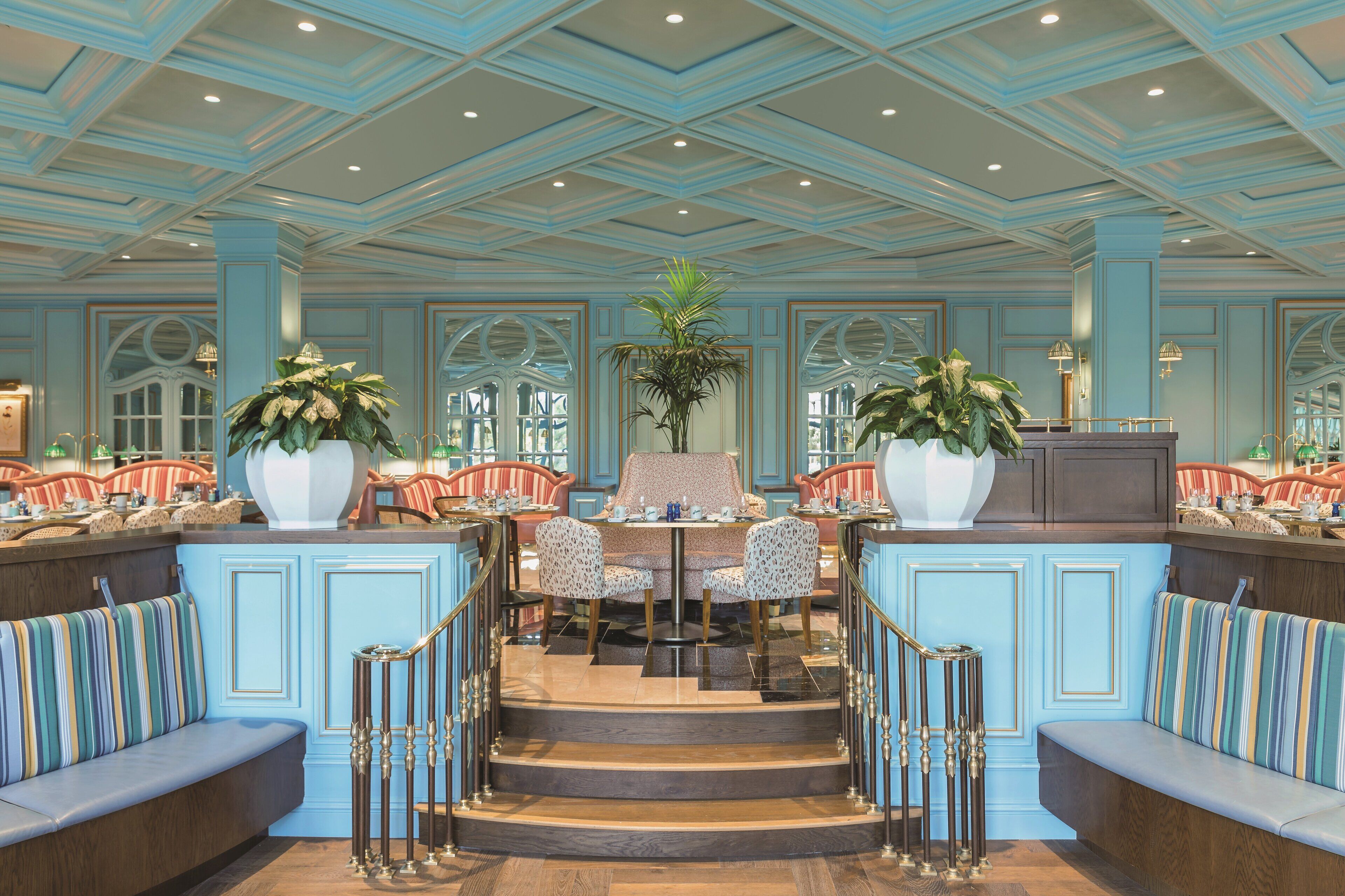 A spacious lobby with a central seating area, a staircase, and a reception desk.