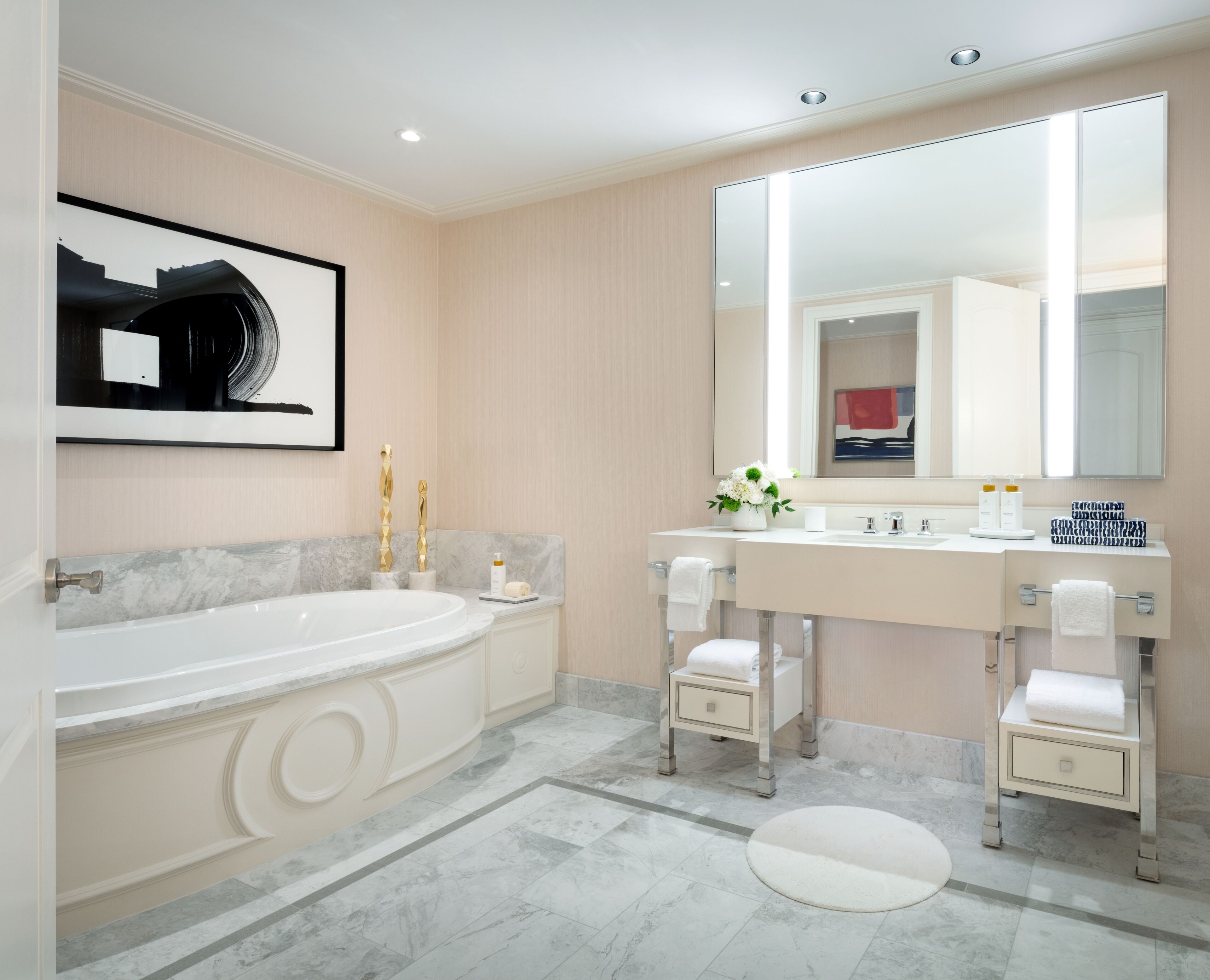A modern bathroom with a large bathtub, a double sink vanity, and a large mirror.