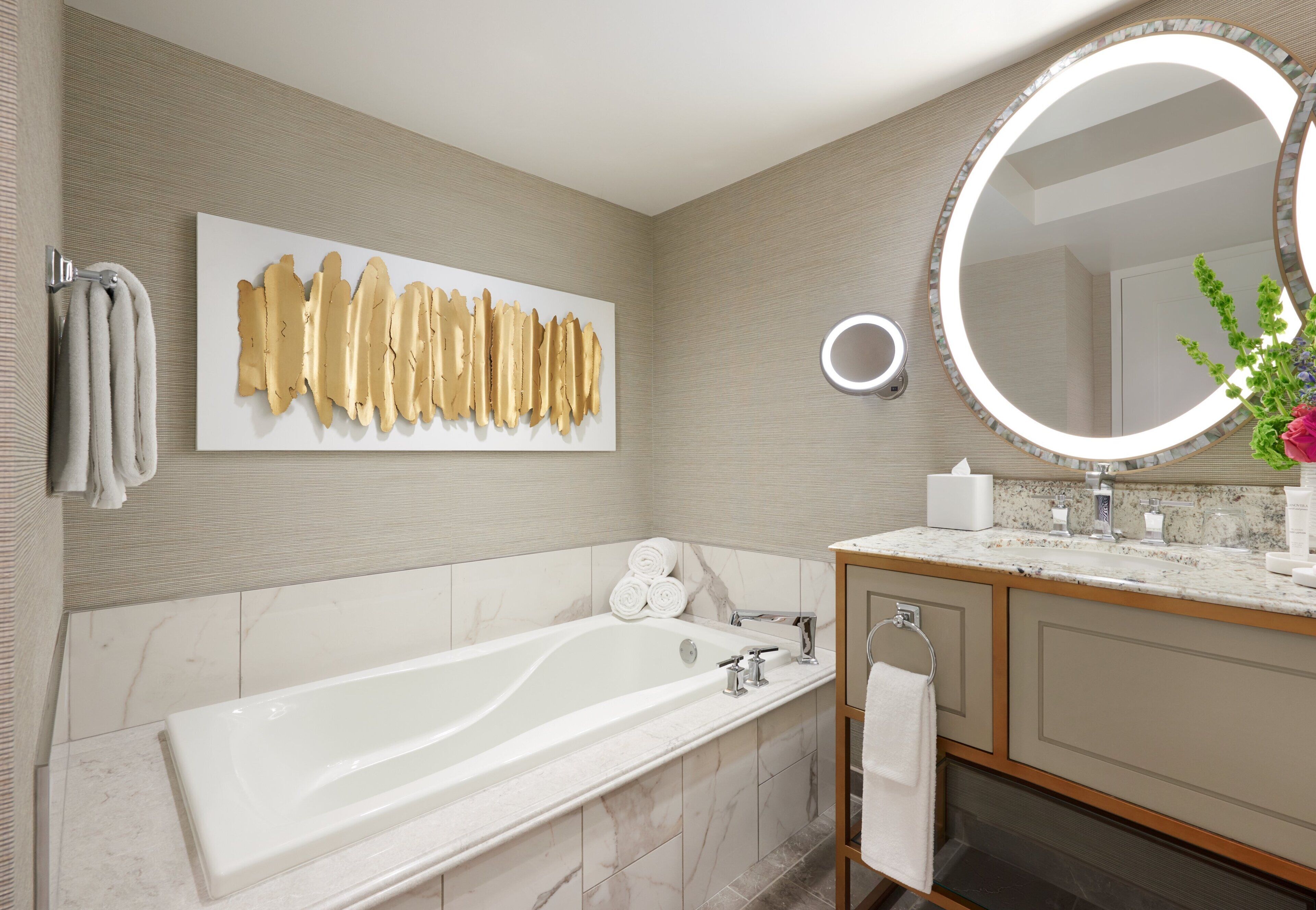 A modern bathroom with a large bathtub, a wall-mounted mirror, and a towel rack.