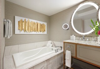 A modern bathroom with a large bathtub, a wall-mounted mirror, and a towel rack.