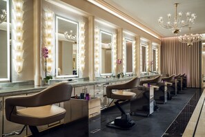 A salon with multiple mirrors, chairs, and a chandelier.