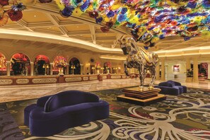 A spacious lobby with a large glass horse sculpture, plush seating, and a ceiling adorned with colorful glass flowers.