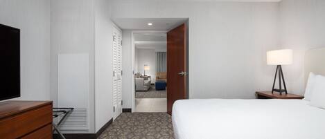 Une chambre d’hôtel avec un lit, une télévision, une commode et un bureau avec une lampe.