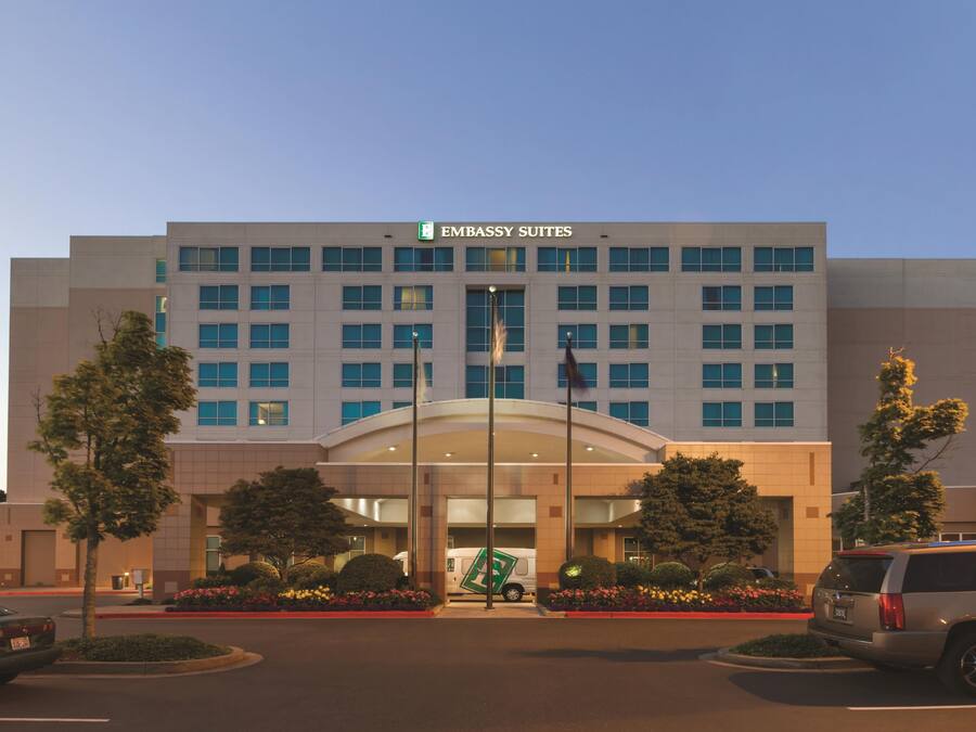 A modern building with a sign reading 'EMBASSY SUITES' at the entrance.