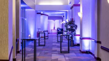 Un pasillo de hotel con alfombra estampada, muebles modernos e iluminación ambiental.