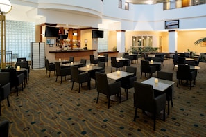A hotel lobby with a bar area, multiple seating arrangements, and a patterned carpet.