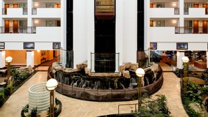 A hotel lobby with a central water feature, multiple floors, and a modern design. - Embassy Suites by Hilton Portland Airport (Portland)