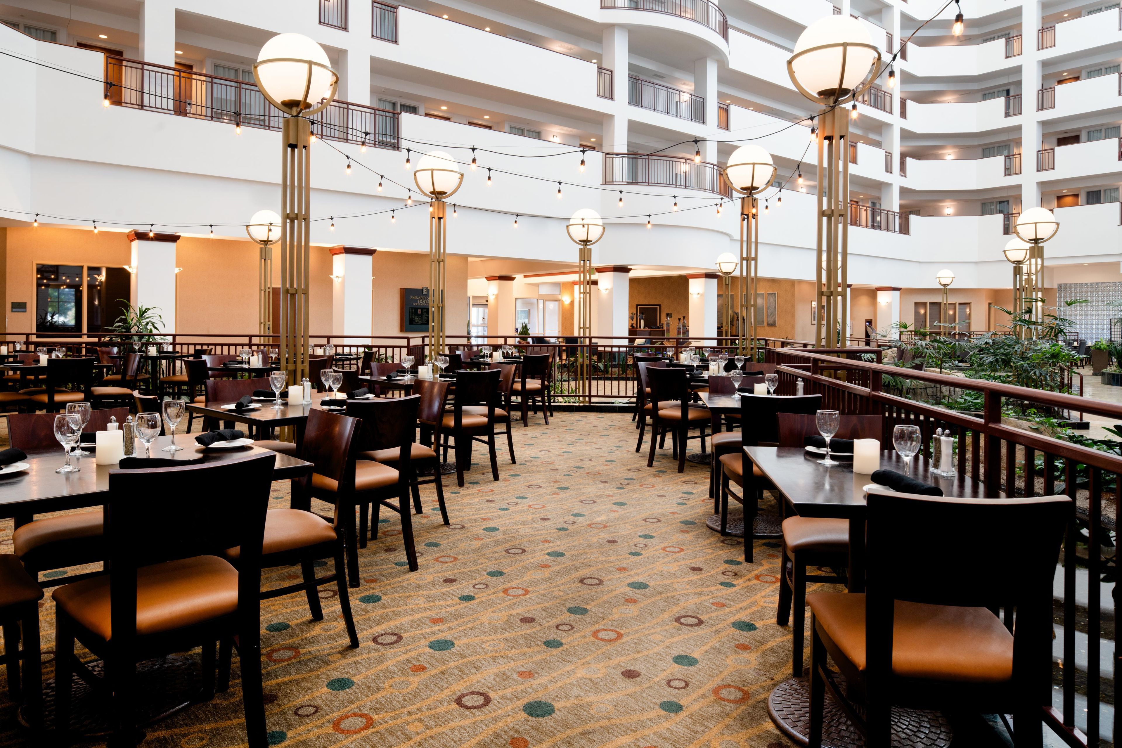 Un comedor de hotel con varios niveles, mesas, sillas e iluminación decorativa.