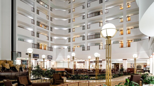 A multi-level hotel lobby with a central atrium, seating areas, and a staircase. - Embassy Suites by Hilton Portland Airport (Portland)