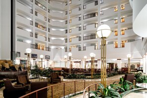 A multi-level hotel lobby with a central atrium, seating areas, and a staircase.