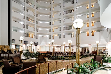 A multi-level hotel lobby with a central atrium, seating areas, and a staircase.