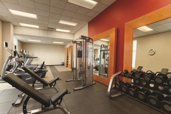 A gym with treadmills, weight machines, and a rack of dumbbells.