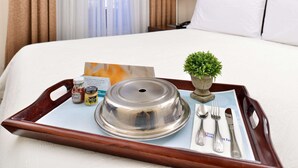 Une chambre d’hôtel avec un lit soigneusement fait, un plateau contenant une casserole couverte, des condiments et des couverts.