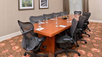 A conference room with a long table, multiple chairs, and a carpeted floor.