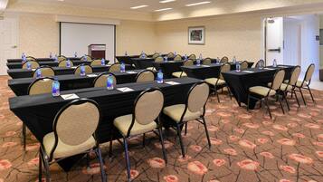 A conference room with multiple tables, chairs, and water bottles.