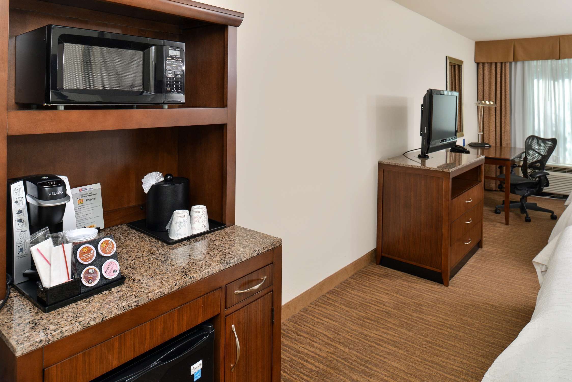 Une chambre d’hôtel équipée d’une kitchenette, d’une télévision, d’un bureau et d’une chaise.
