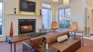 Un salon moderne doté d’une cheminée, d’un canapé en cuir, de deux fauteuils, d’une table basse et d’un téléviseur à écran plat fixé au-dessus de la cheminée.