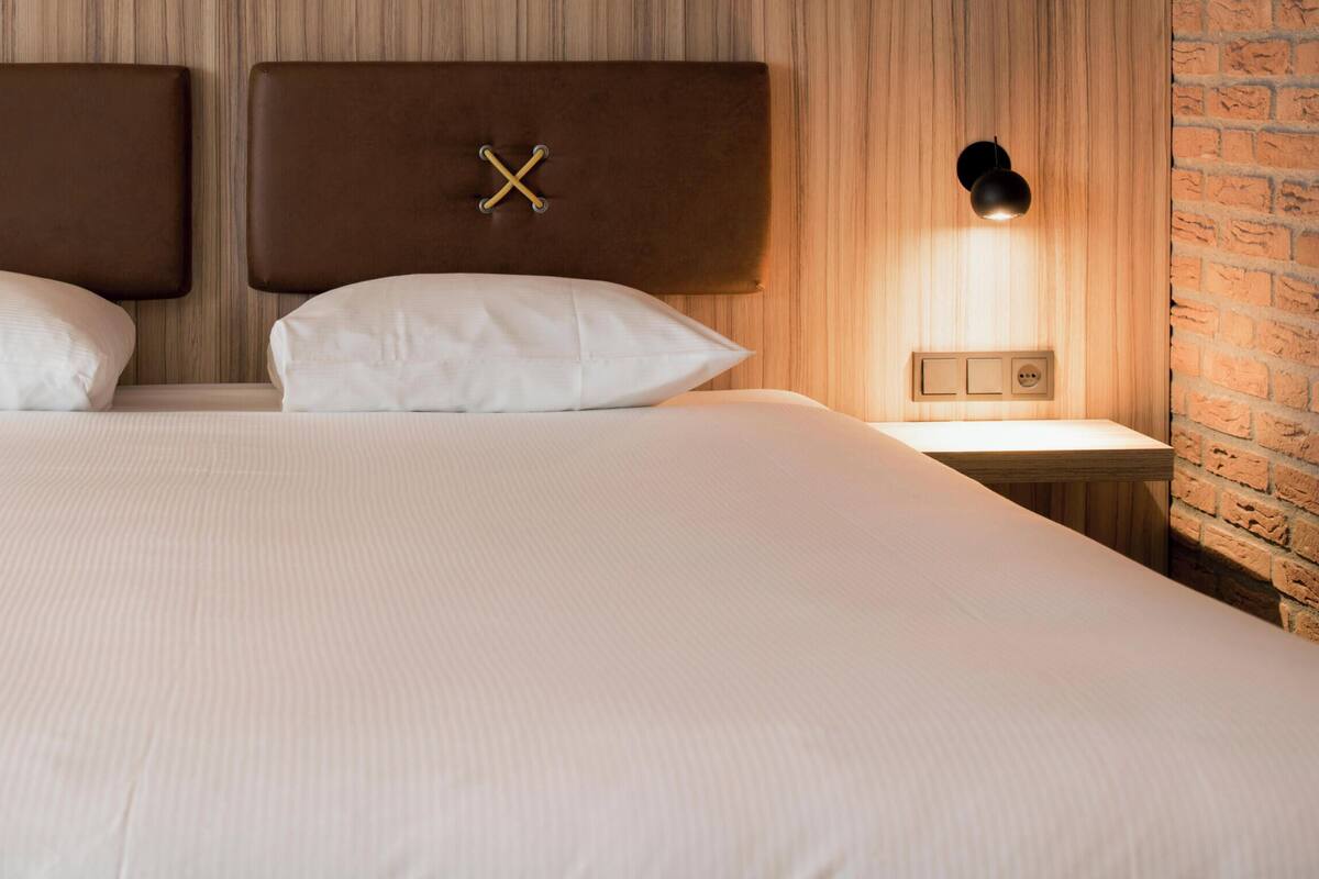 A hotel room with a large bed, two bedside lamps, and a motivational quote on the wall.