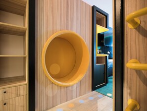 A modern room with a circular yellow seating area, wooden walls, and a visible television.