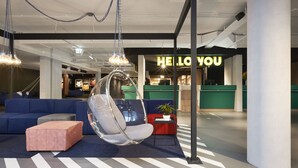 A modern lounge area with a hanging chair, a sofa, and a small table with a plant. - HUP (Mierlo)