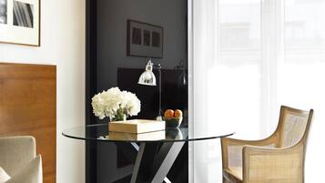 Una habitación moderna con una mesa de vidrio, una silla de mimbre, una lámpara y un jarrón con flores.