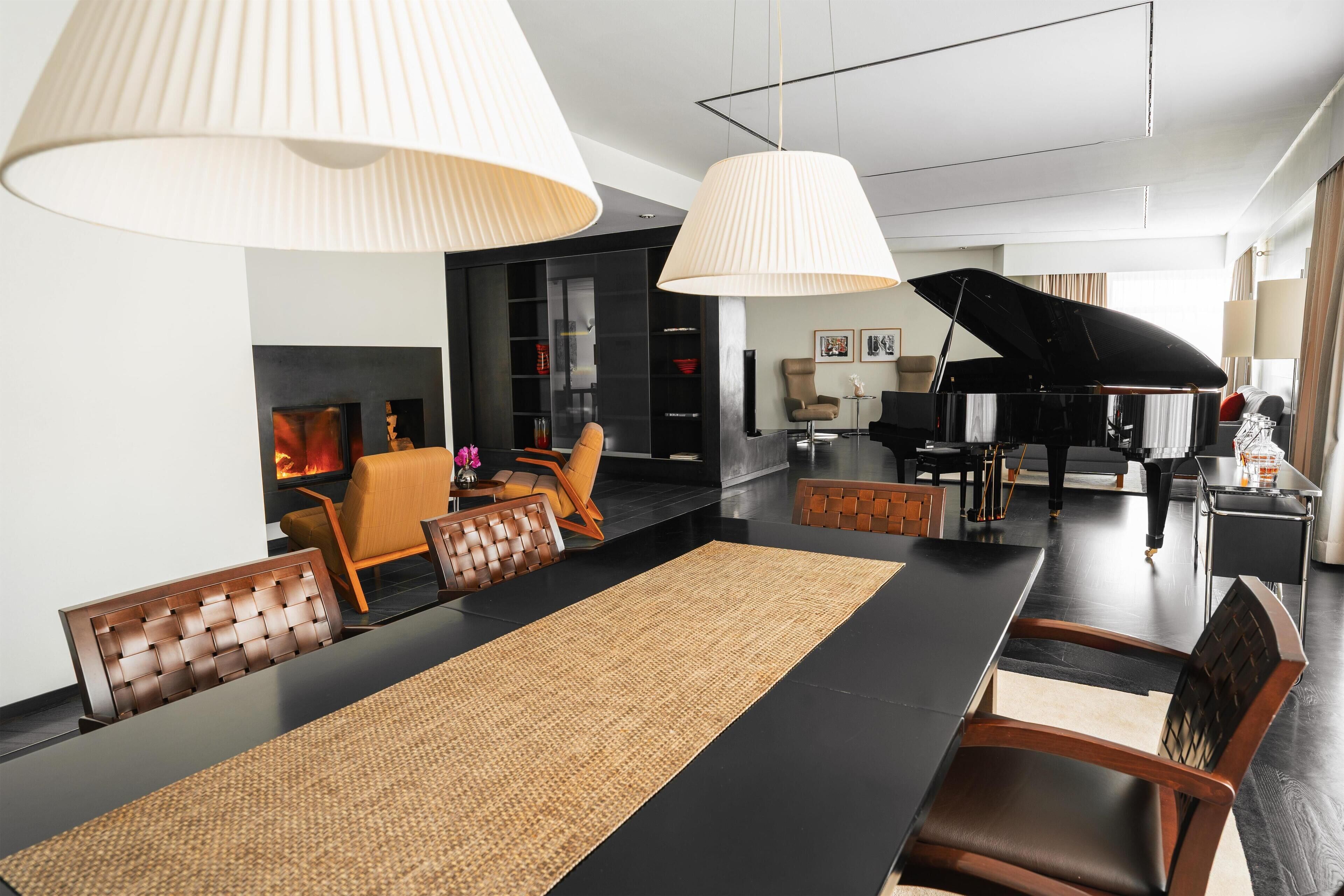 Una sala de estar moderna con comedor, chimenea y un piano de cola.