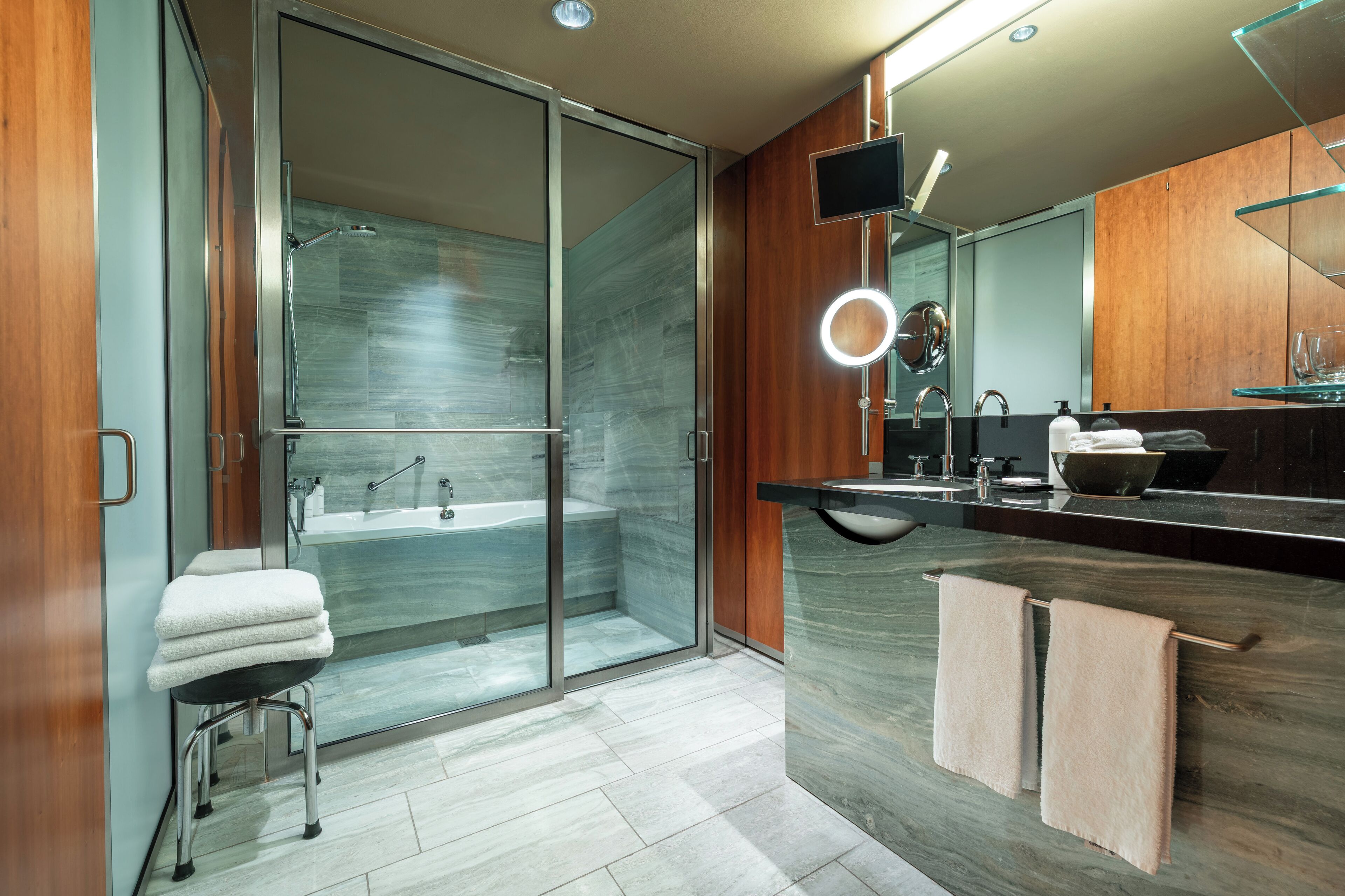 A modern bathroom with a glass shower enclosure, a vanity with a mirror, and a towel rack.