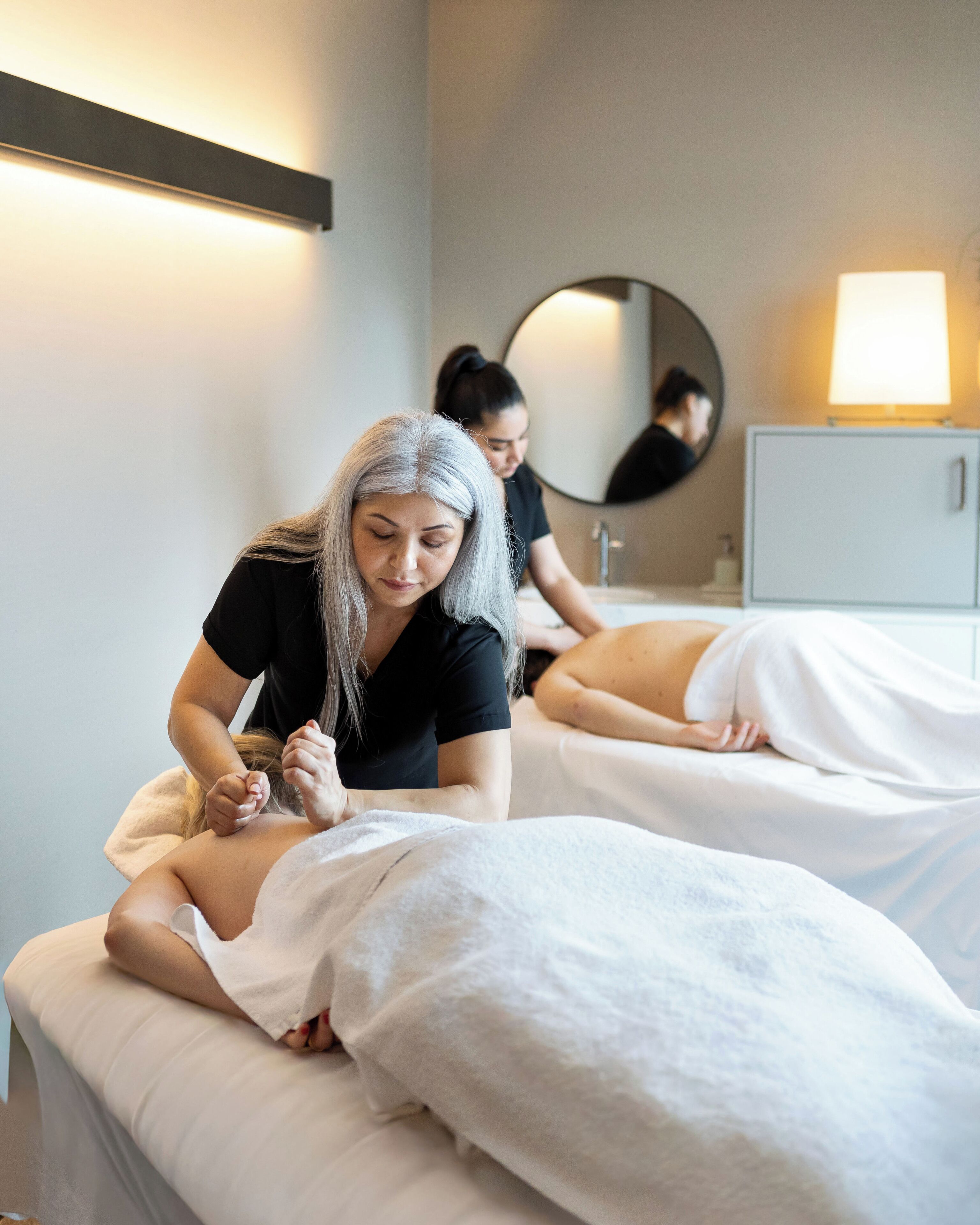 Sala de masajes con dos clientes y un terapeuta.