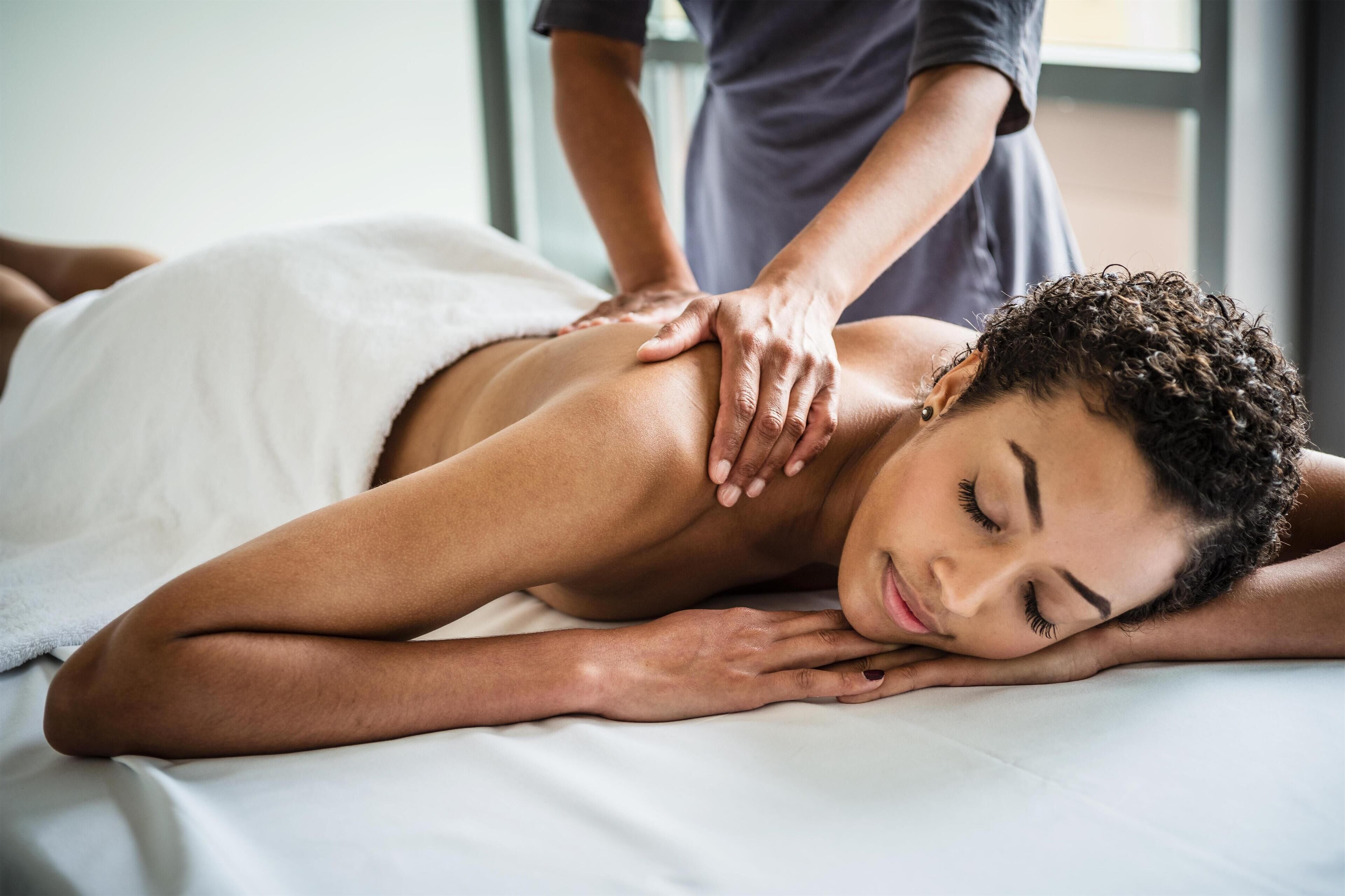 A person receiving a back massage on a bed.