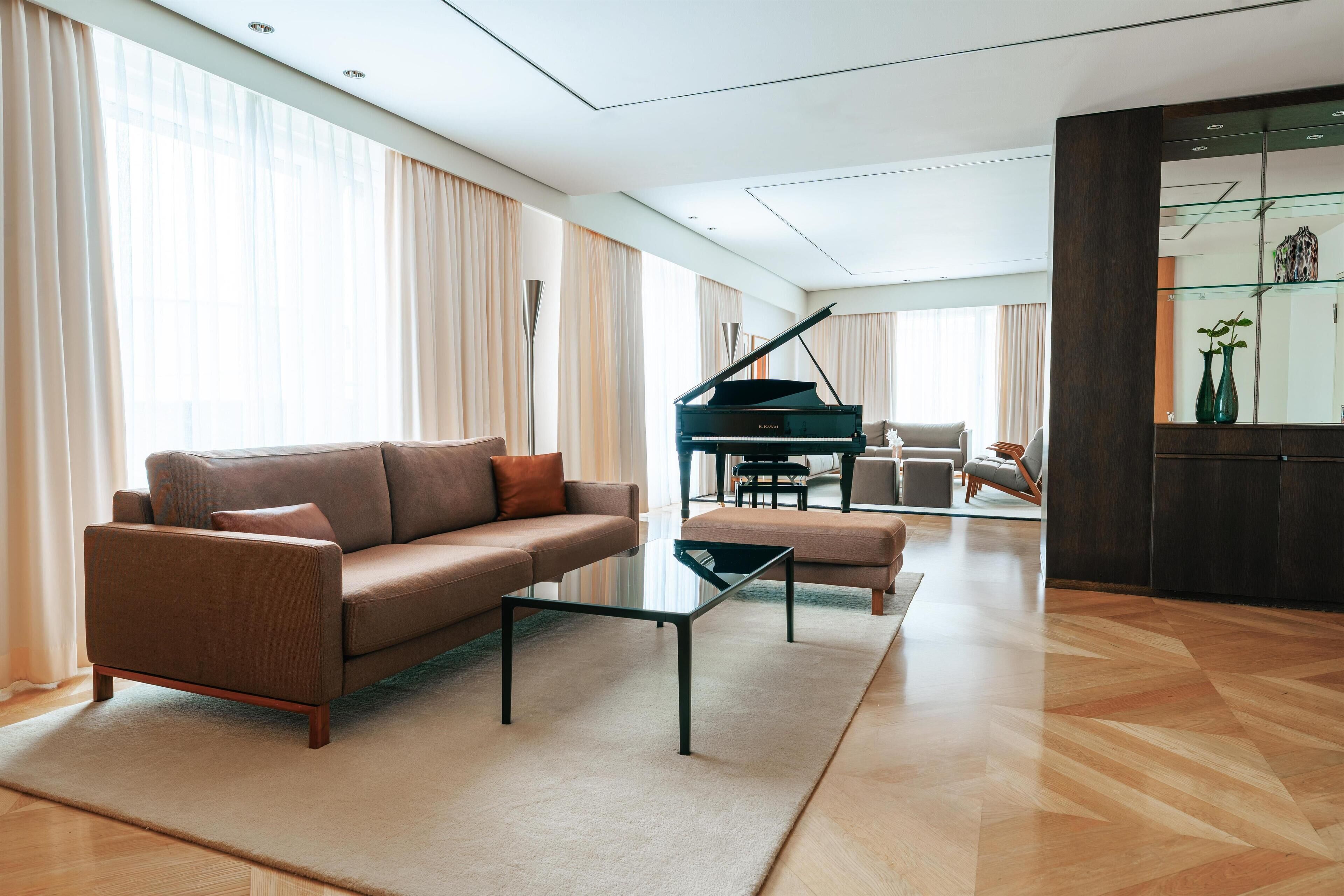 A modern living room with a grand piano, a sofa, and a coffee table.