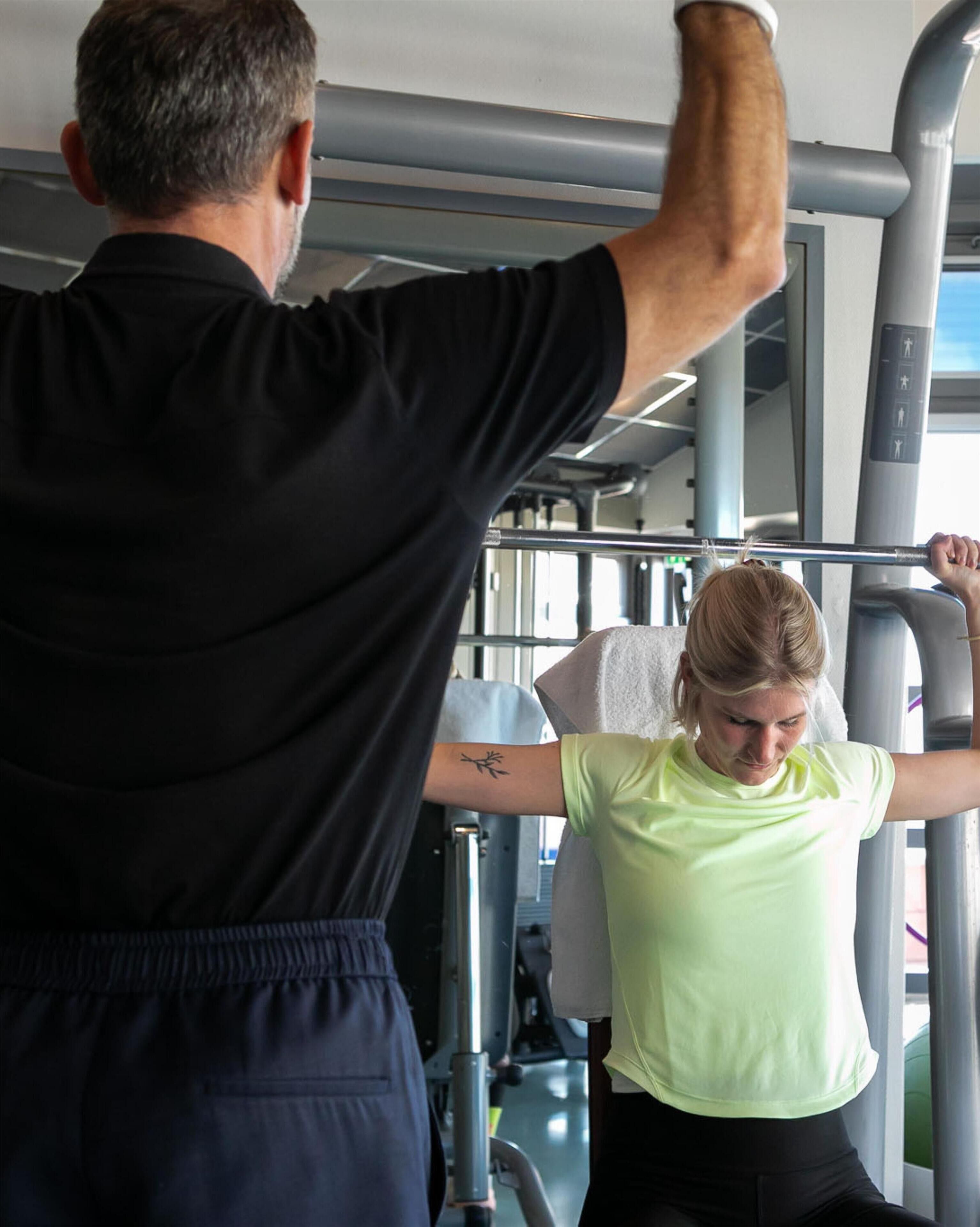 Une salle de sport équipée de matériel d'exercice, où une personne s'entraîne à l'aide d'un appareil à câbles.