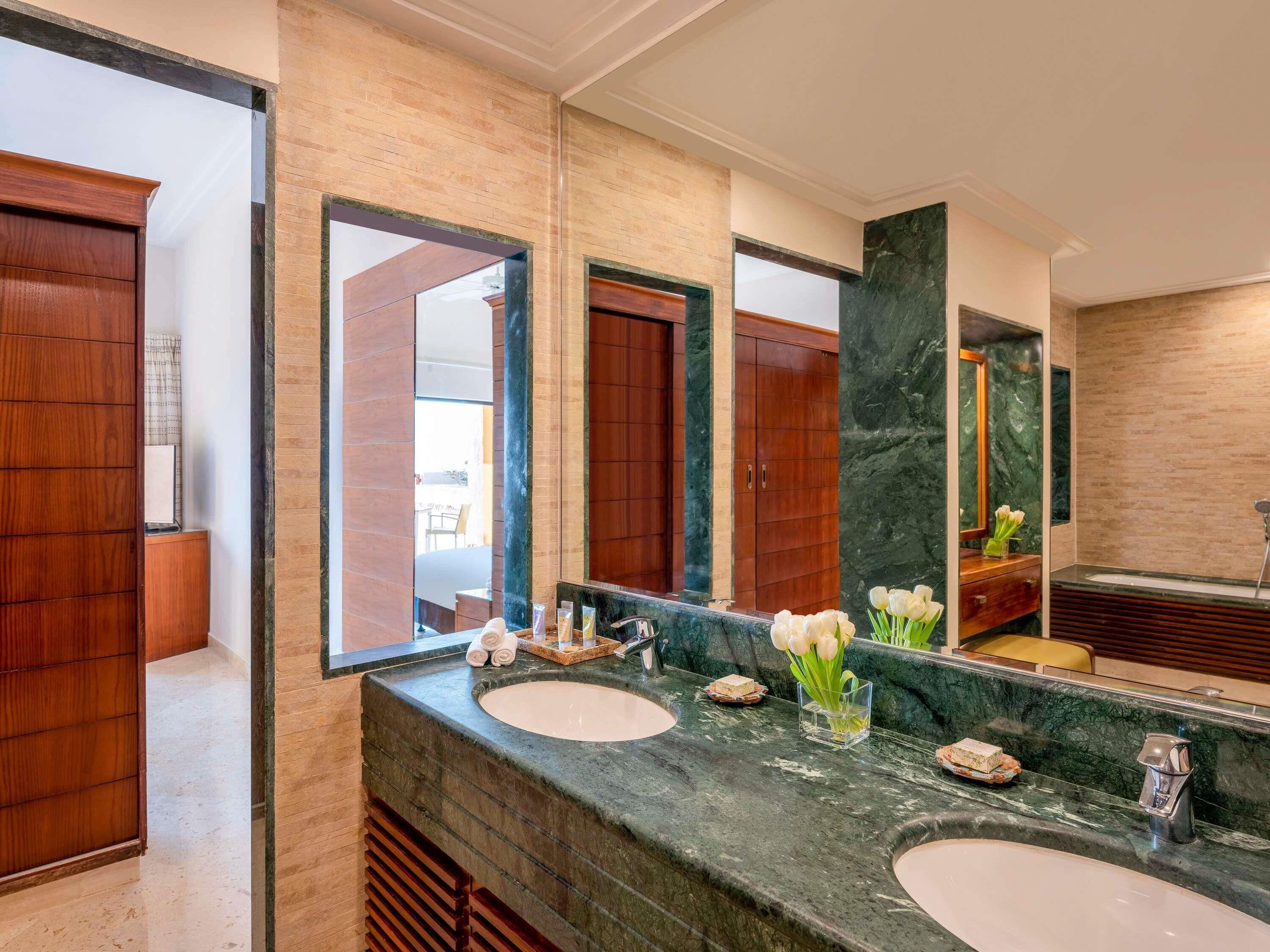 A bathroom with two sinks, a large mirror, wooden cabinets, and a marble countertop.