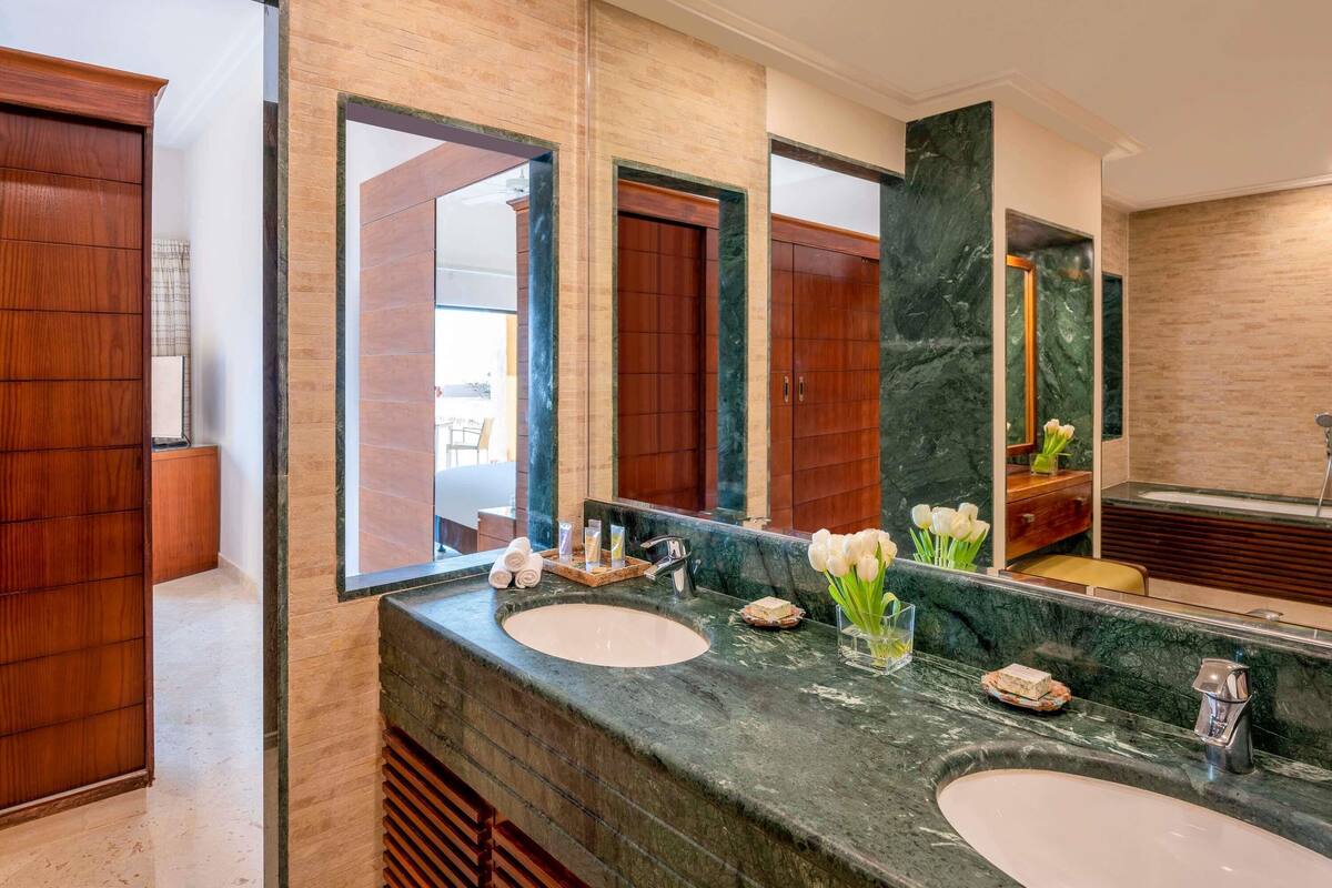 A bathroom with two sinks, a large mirror, wooden cabinets, and a marble countertop.