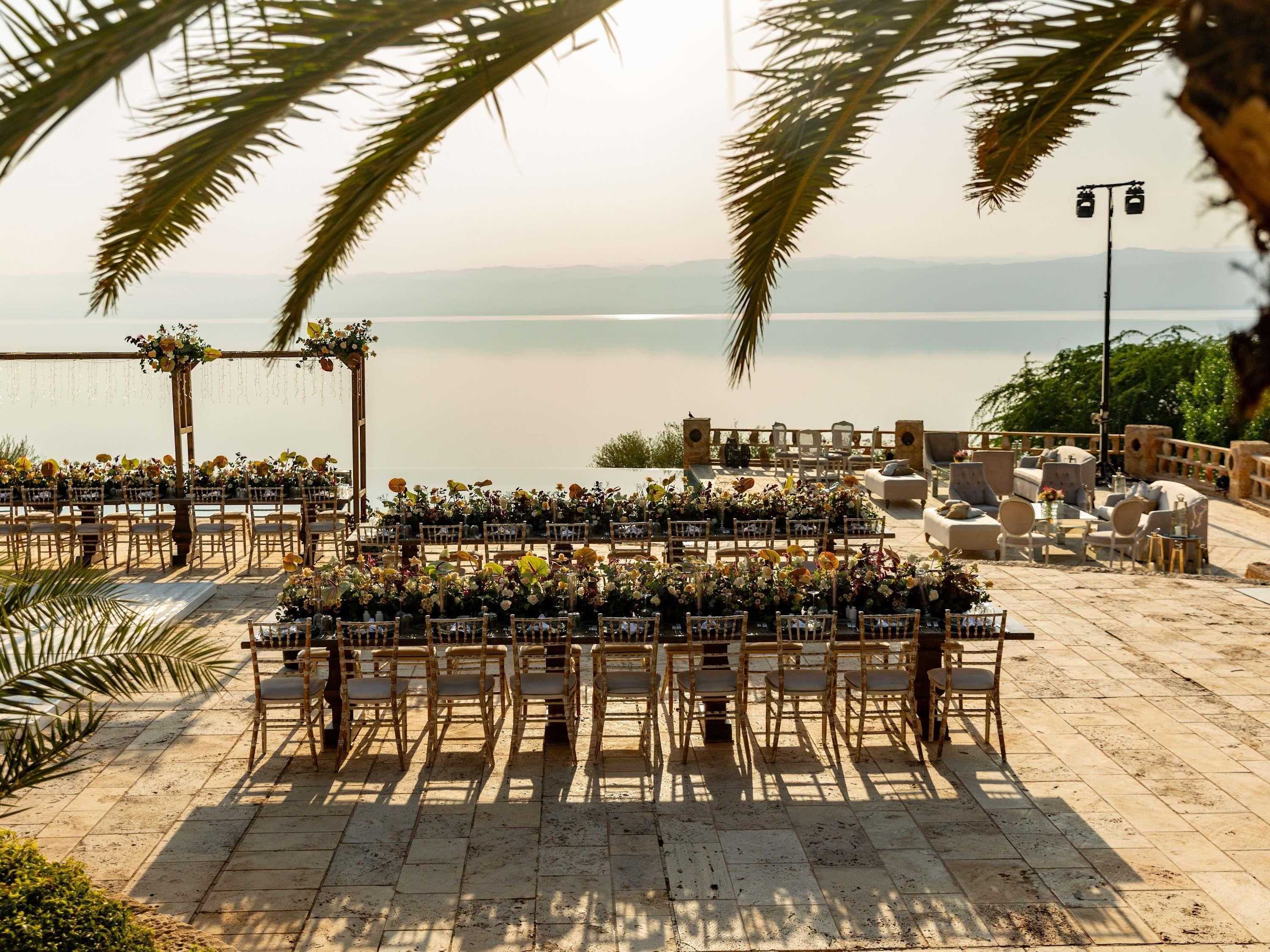 An outdoor wedding setup with chairs and tables arranged for guests, overlooking a body of water.